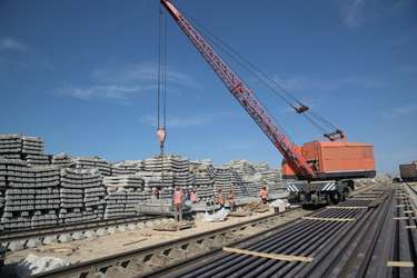 Ground imagery of a DMR construction site featuring the large red crane and stacks of concrete rail ties. Imagery via KTZ official Telegram Channel.